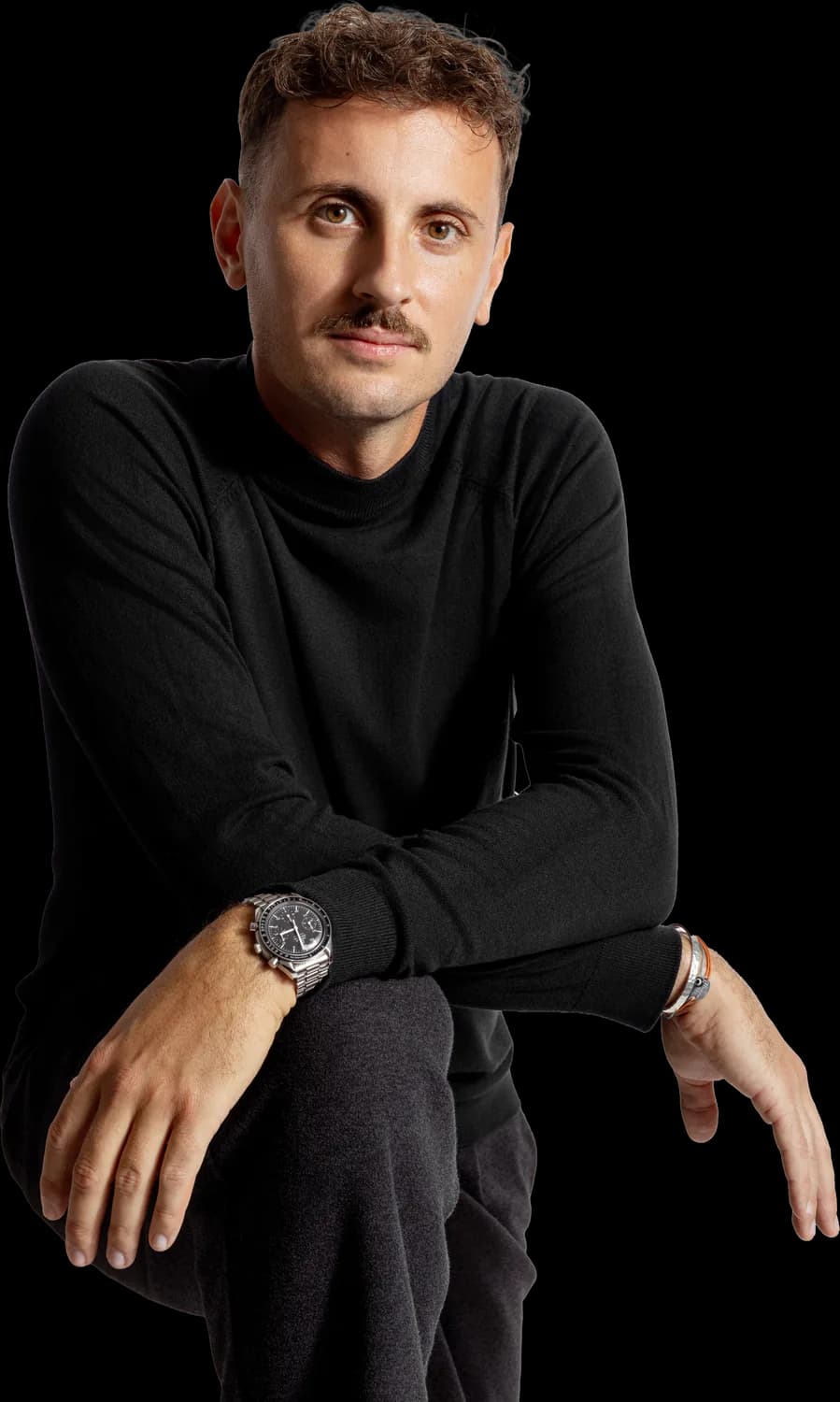 Portrait détouré de Roman Blum, fondateur du studio SIEKLE près d'Avignon, pull noir à col montant, bras posés sur le genou, regard face caméra