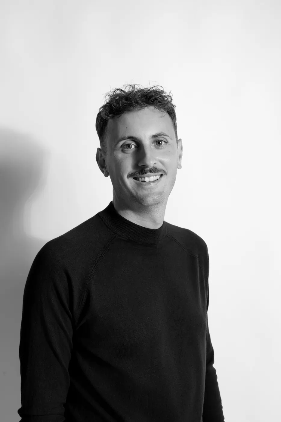Portrait souriant en noir et blanc de Roman Blum, consultant en communication à Avignon, pull noir à col montant